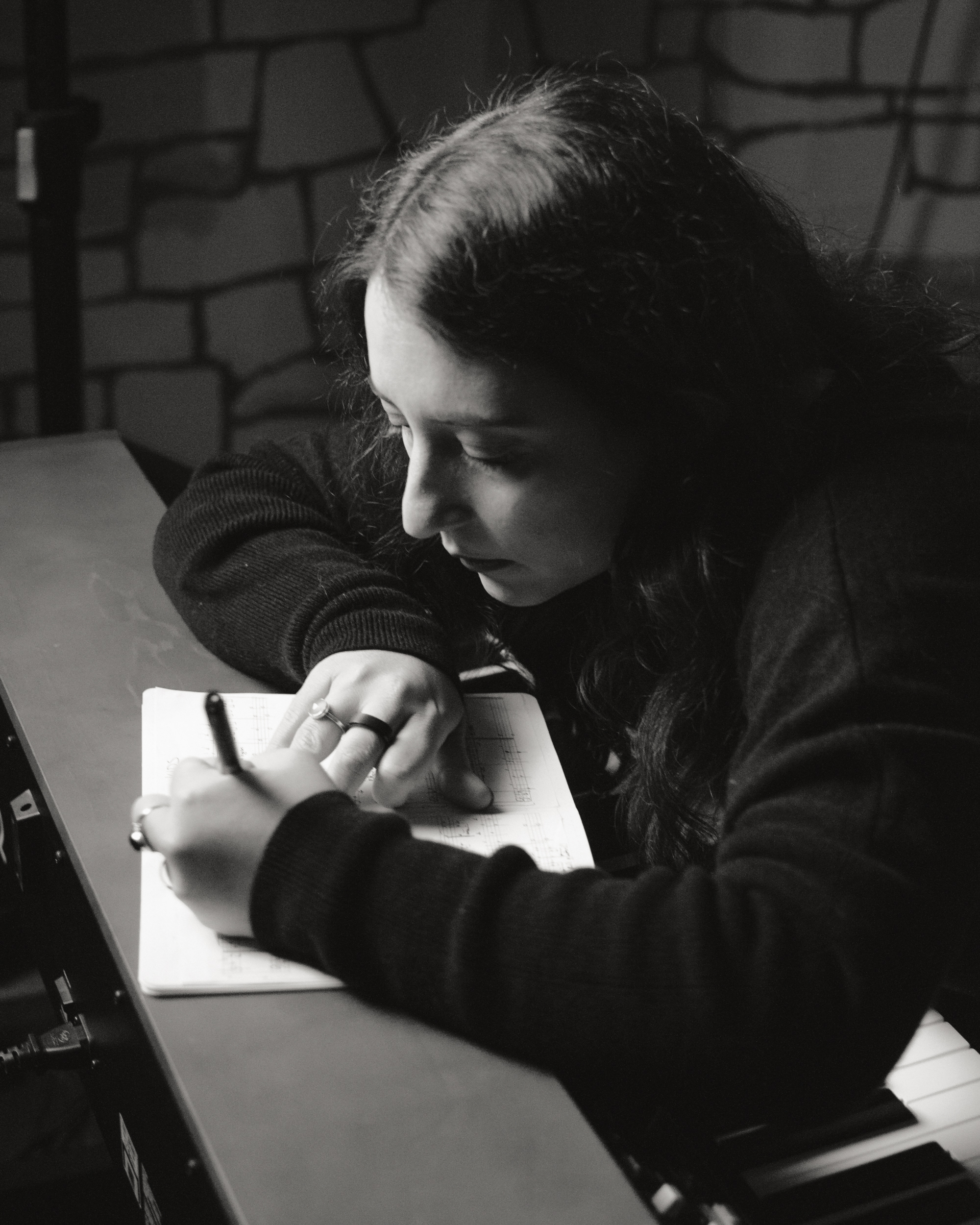 Skùmaskot writing in a notebook at the piano