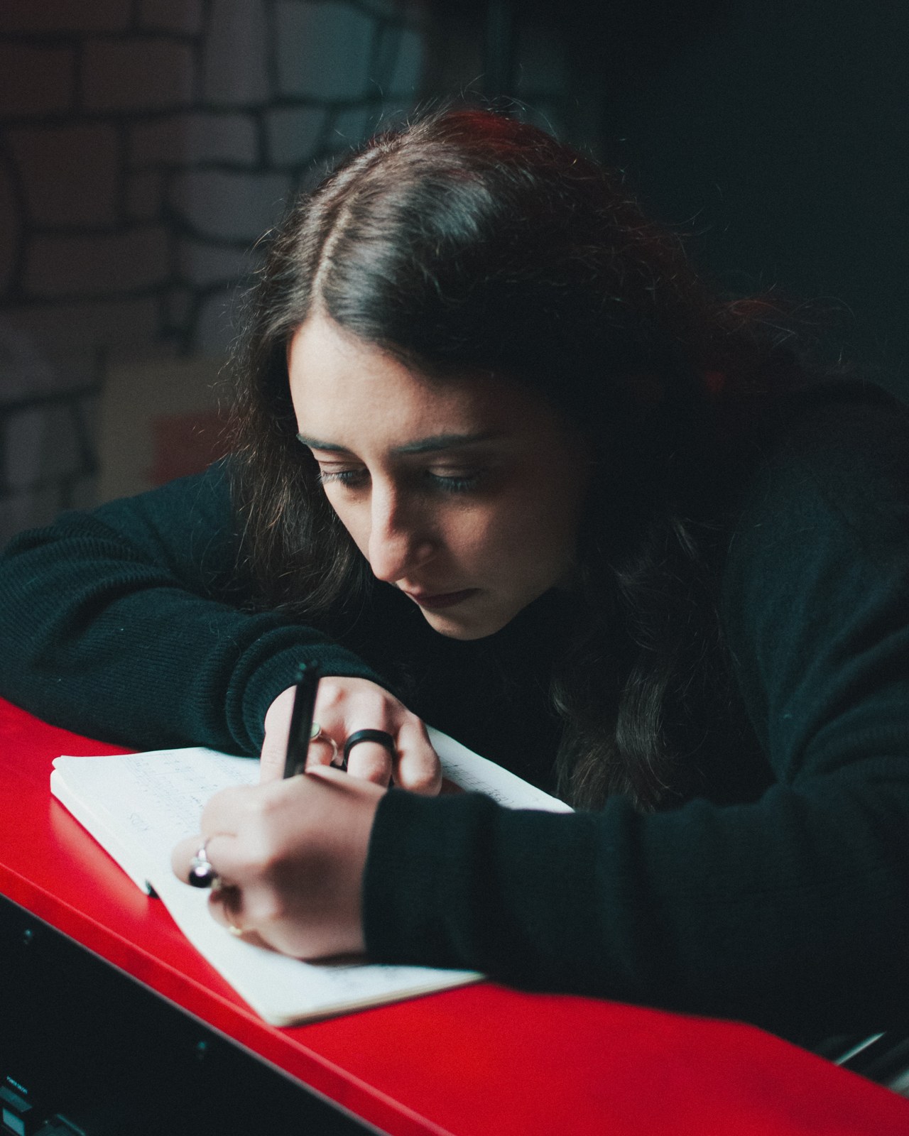 Skùmaskot writing in a notebook at the piano